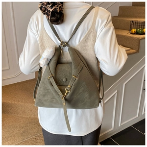 Rear view of vintage dark green backpack with gold hardware and rabbit charm on a model