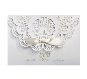 Detail of laser-cut wedding invitation with cream pearlescent texture and silk bow
