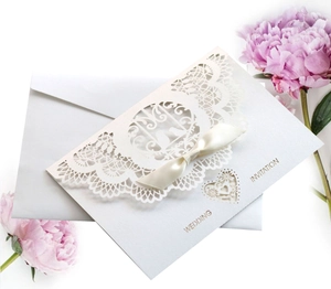 Elegant laser-cut hollow heart wedding invitation with a satin bow and envelope