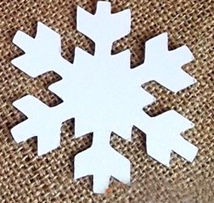White hexagonal snowflake cutout for winter decoration on brown burlap background