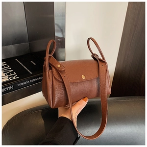 Detail of brown lychee grain leather handbag with gold circular clasp and wrapped handle