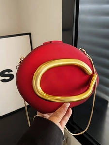 Red oval crossbody evening bag featuring a prominent gold C-shaped handle and chain strap