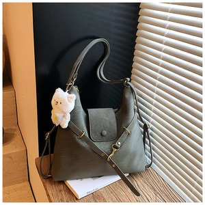 Detail of dark green lychee leather bag with gold hardware and plush cat charm