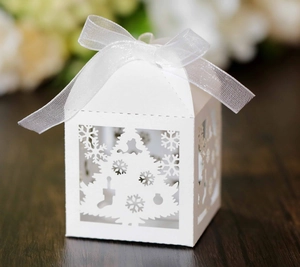 Detail of laser-cut Christmas candy box with snowflake patterns and white ribbon bow
