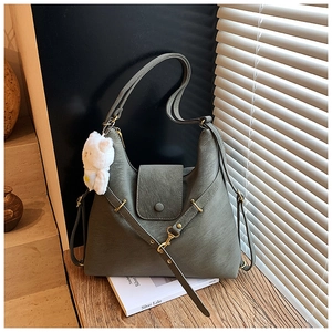 Detailed close-up of olive green PU leather tote bag with plush bear charm and gold buckle
