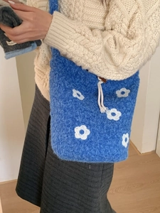 Blue knit bucket bag with white flowers and drawstring for women in a cozy winter style