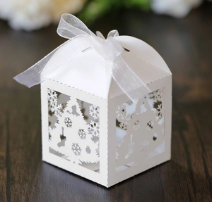 Detail of white laser-cut Christmas favor box with snowflake and tree patterns