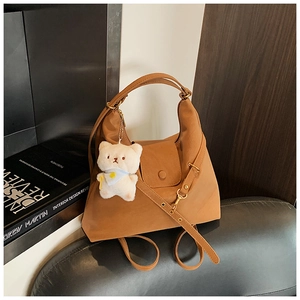 Detail of vintage brown tote with magnetic pocket and plush bear charm on leather seat