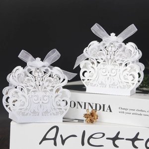 Detalle de caja de dulces de encaje blanco cortado con láser y lazo de cinta de organza