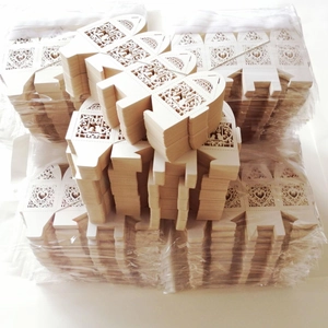 Bulk laser cut cream hollow heart favor boxes with intricate floral patterns in packaging
