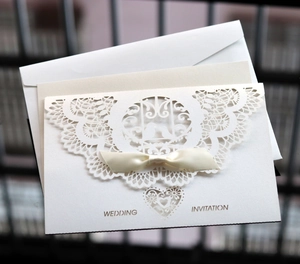Elegant ivory laser cut lace wedding invitation with ribbon bow and envelope
