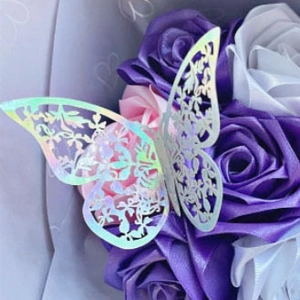 Macro shot of 3D iridescent laser-cut butterfly decorations nestled in artificial roses