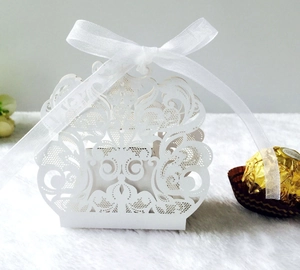 Detalle caja de boda blanca cortada con láser con motivos de vid y una cinta de seda