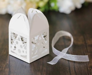 Detailed laser cut white Christmas gift box with tree patterns and ribbon on wood