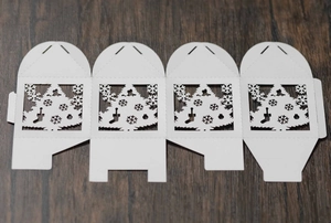 Flat lay of white laser-cut Christmas candy box template with festive cutout patterns