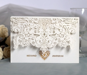 Detailed laser-cut wedding invitation with hollow floral patterns and gold heart inserts