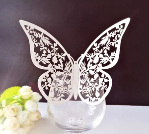 Elegant white laser-cut butterfly decoration card on a glass rim for wedding decor