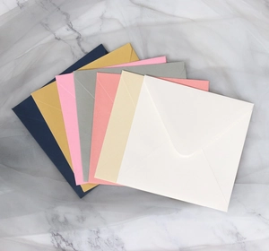 Detailed fan arrangement of square envelopes in seven pastel colors on marble background