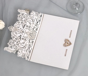 Detail of laser-cut floral lace and heart-shaped cutout on white wedding invitation card