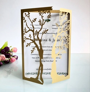 Macro shot of laser-cut tree of life design on cream and gold wedding invitation