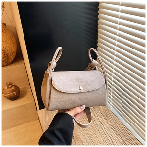 Detailed macro shot of khaki lychee leather handbag with golden round metal snap buckle