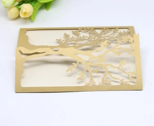 Detail of laser-cut gold pearlescent paper invitation card with intricate tree design