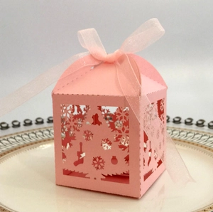 Macro detail of pink laser-cut Christmas gift box with snowflake patterns and ribbon