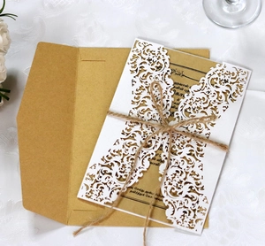 Laser cut floral invitation set with kraft paper card and hemp rope on white tablecloth