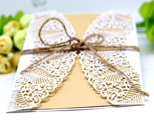 Detail of laser-cut white lace invitation with kraft paper and hemp rope bow