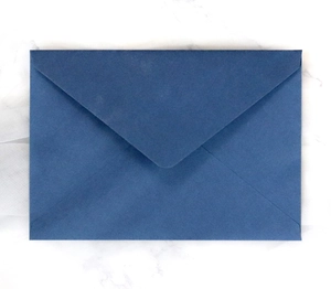 Detail of premium dark blue textured envelope with V-flap design on white marble