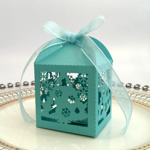Detail of laser-cut light teal Christmas candy box with snowflake pattern and ribbon bow