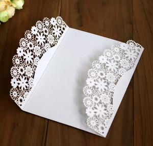 Détail de découpe laser motif marguerite sur pochette d'invitation blanc nacré