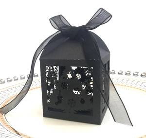 Macro view of a black laser-cut Christmas tree gift box with elegant organza ribbon on a plate
