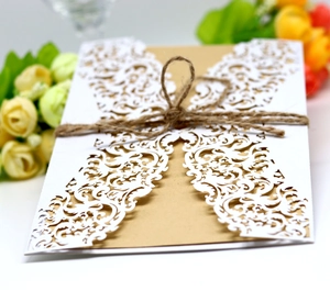 Detail of laser-cut lace invitation with kraft paper insert and twine bow decoration