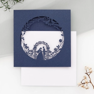Detail of laser-cut navy blue pearlescent paper wedding invitation with bird and floral pattern