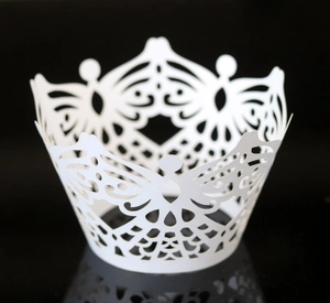 Macro detail of laser-cut white butterfly cupcake wrappers with elegant lace pattern