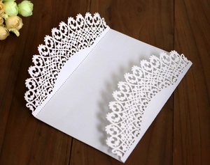 Macro detail of laser-cut filigree pattern on white wedding invitation card cover