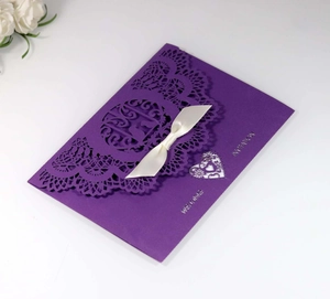 Detail of laser-cut wedding invitation in dark purple with a satin bow and silver font