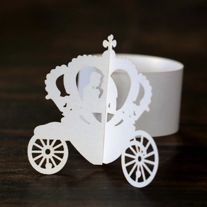 Macro detail of laser-cut pearl paper napkin ring featuring a royal carriage and couple