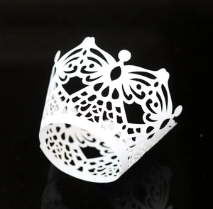 Macro view of white crown-shaped laser-cut cupcake wrapper with intricate floral patterns