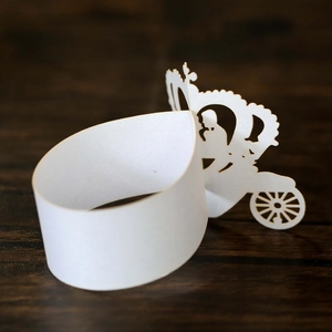 Laser-cut white paper napkin ring featuring a detailed hollow carriage and crown design