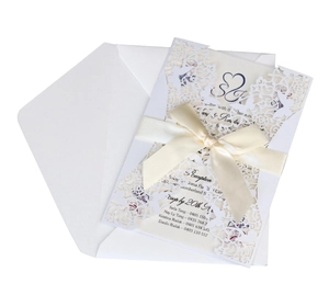 Detail of white laser-cut butterfly wedding invitation with ribbon and envelope set