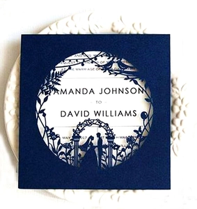 Detail of laser-cut navy blue wedding invitation with intricate floral and couple silhouette