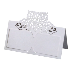 Detail view of white laser-cut place cards with heart pattern for wedding tables