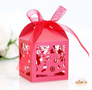 Detail of red laser-cut Christmas gift box with snowflake patterns and organza ribbon