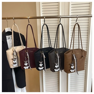 Close-up of five leather bucket bags in various colors with schnauzer charms on display