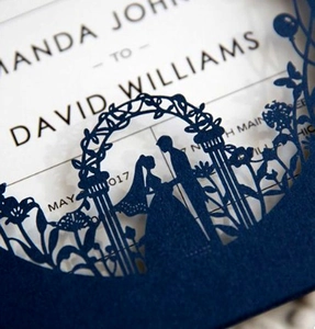 Detail of laser-cut navy blue wedding invitation with floral pattern and bride silhouette