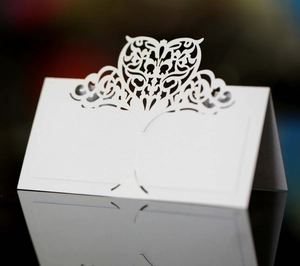 Macro detail of laser-cut heart pattern on white pearlescent paper wedding place card