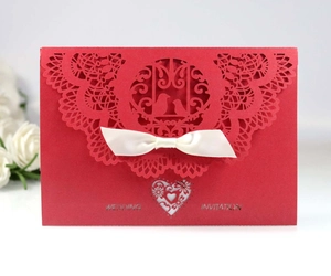 Detailed laser-cut red wedding invitation with vintage lace pattern and white satin bow