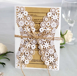 Detail view of laser-cut white floral invitation card with kraft paper and hemp rope bow
